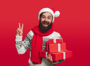 Noel hediyeli mutlu adam barış işareti gösteriyor.