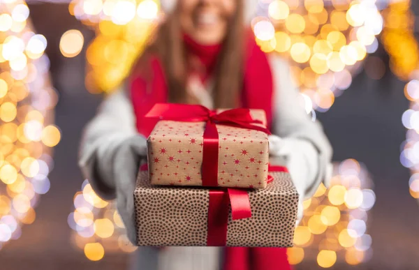 Unrecognizable woman offering Christmas gifts to camera — Stock Photo, Image