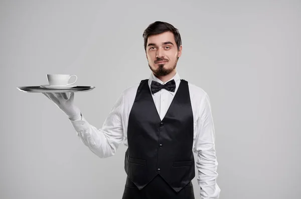 Профессиональный официант с чашкой напитка на подносе — стоковое фото