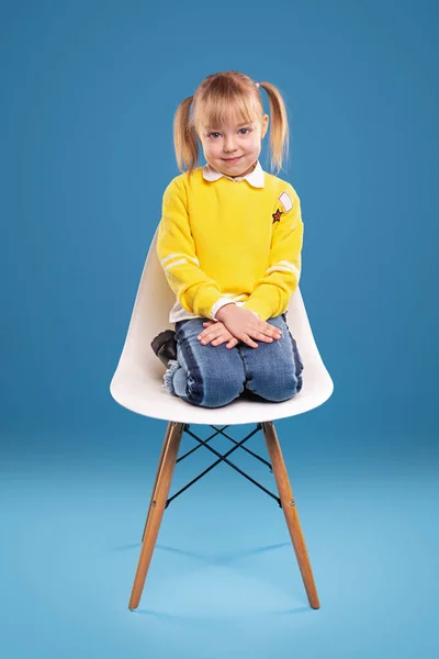 Adorável menina em roupa casual sentado na cadeira — Fotografia de Stock