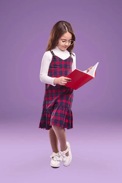 Розумна школярка в уніформі підручника для читання — стокове фото