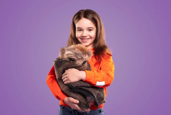 Menina feliz abraçando coelho envolto em pano — Fotografia de Stock