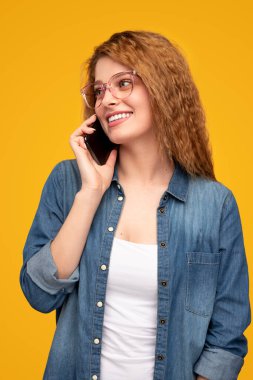 Neşeli genç bayan telefonda konuşuyor.