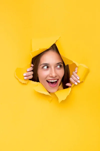Mulher excitada através do furo de papel rasgado — Fotografia de Stock