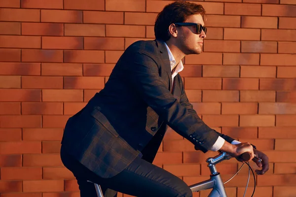 Confiado hombre de negocios montar bicicleta contra la pared de ladrillo —  Fotos de Stock