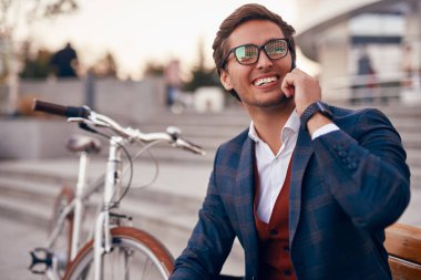 Şehirde telefonda bisiklet sohbeti yapan mutlu resmi adam.