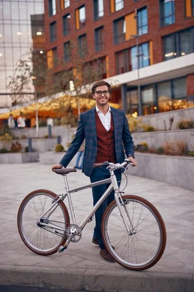 Kaldırımda bisikleti olan modern neşeli iş adamı.