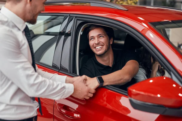 Šťastný klient a dealer potřást rukou v blízkosti nového auta — Stock fotografie