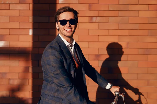 Alegre empresario moderno en bicicleta de la ciudad a la luz del sol —  Fotos de Stock