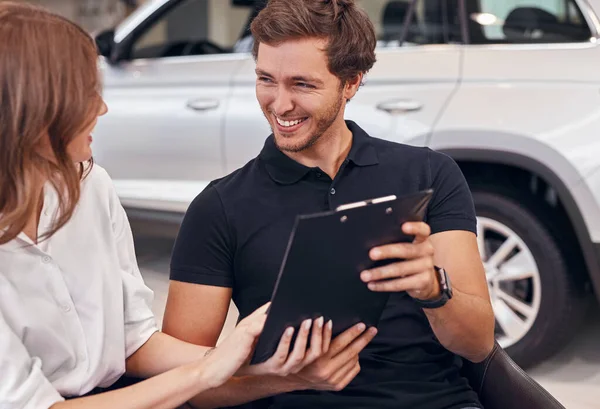 Feliz casal leitura contrato no carro concessionária — Fotografia de Stock