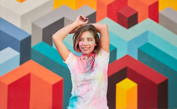 Vrolijke jonge vrouw in kleurrijke t-shirt staande tegen graffiti muur — Stockfoto