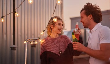 Neşeli arkadaşlar parti sırasında bira şişelerini tokuşturuyor.