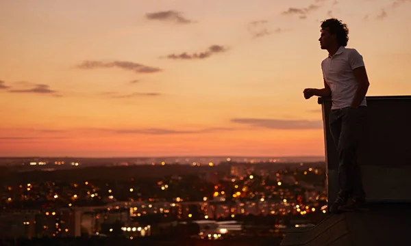 Hombre disfrutando de la puesta de sol desde la azotea del edificio de la ciudad —  Fotos de Stock