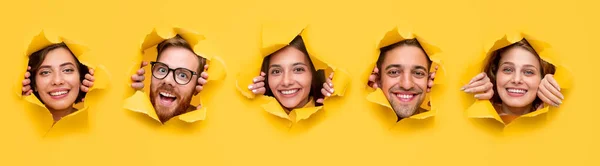 Cheerful young friends tearing holes in yellow paper — ストック写真