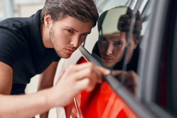 Muž kontroluje nové auto v prodejně — Stock fotografie