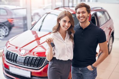 Satıcılıkta yeni arabanın yanında duran mutlu çift