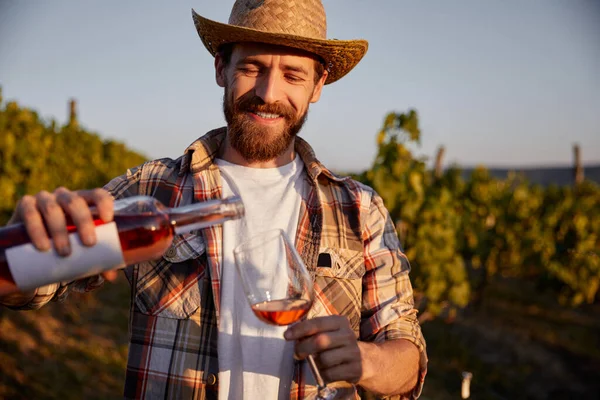 Cheerful winemaker pouring wine on farm — Stock Photo, Image
