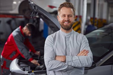 Tamirci yakınındaki kendinden emin müşteri araba tamir ediyor.