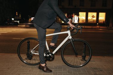 Gece vakti bisiklet süren takım elbiseli modern bir işadamı.