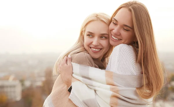 Feliz namoradas com cachecol quente abraçando no dia frio — Fotografia de Stock