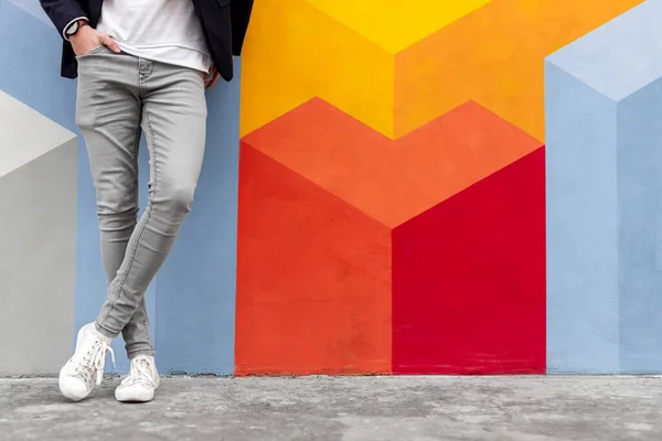 Hombre con estilo en jeans de moda de pie cerca de la pared —  Fotos de Stock