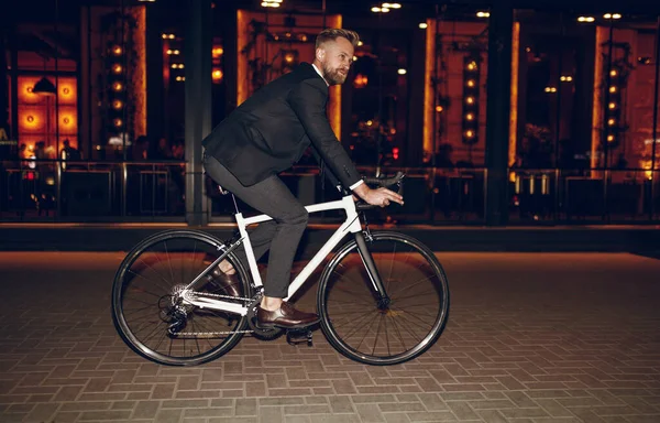 Elegante hombre de negocios montar en bicicleta en la ciudad de noche — Foto de Stock