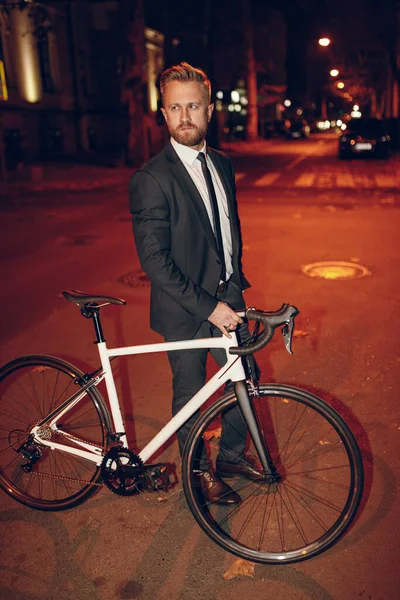 Elegante hombre de traje formal con bicicleta en la calle nocturna — Foto de Stock