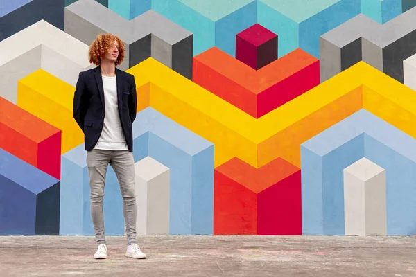 Elegante chico millennial en traje de moda de pie cerca de la pared colorida —  Fotos de Stock