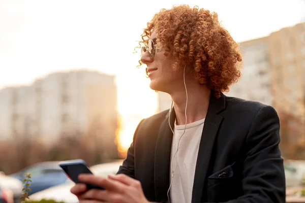 Hombre de moda con smartphone y auriculares descansando en la calle — Foto de Stock