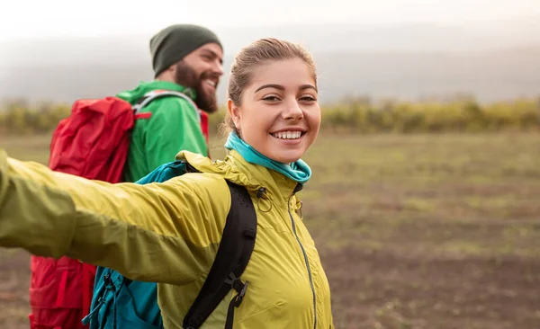 Cheerful couple with backpacks hiking in autumn nature — Stock Photo, Image