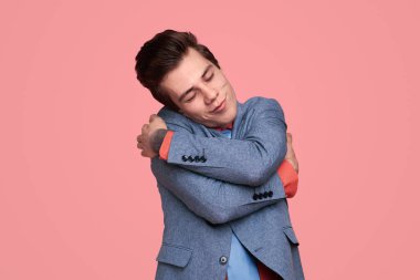 Hayalperest genç adam kendini kucaklıyor.