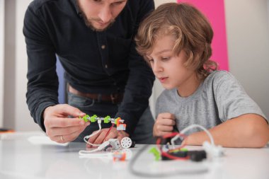 Öğretmen ve çocuk okulda robot yapıyor.