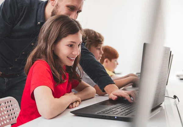 Happy schoolmeisje met leraar werken op laptop tijdens de les — Stockfoto