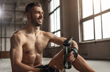 Mutlu erkek sporcu antrenman sırasında suyla dinleniyor.