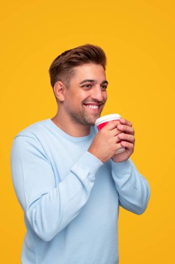 Mutlu genç adam sıcak içkinin tadını çıkarıyor.