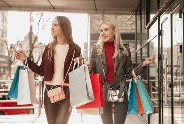 Alışveriş yaptıktan sonra sokakta yürüyen mutlu genç kadınlar