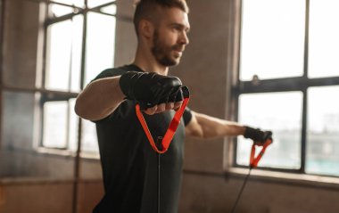 Esnek iplerle egzersiz yapan güçlü bir sporcu.