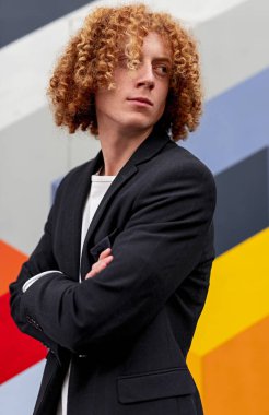 Renkli duvarlara karşı kıvırcık saçlı, kendine güvenen bir adam.