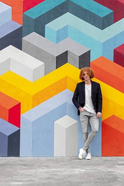 Renkli duvarın yanında duran şık genç adam