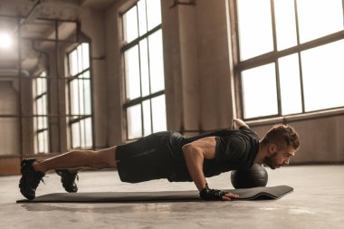 Kaslı sporcu topla şınav çekiyor.