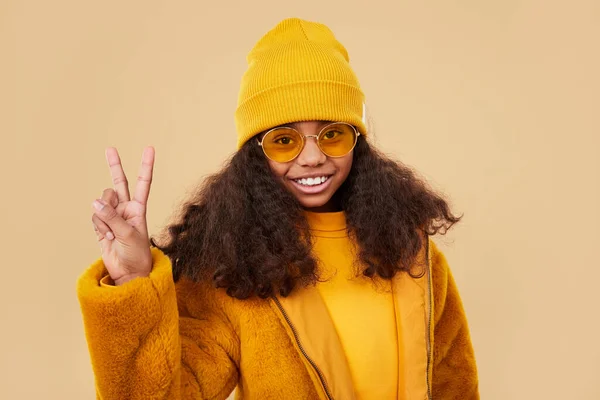 Happy black girl in yellow outfit making V sign Stock Picture