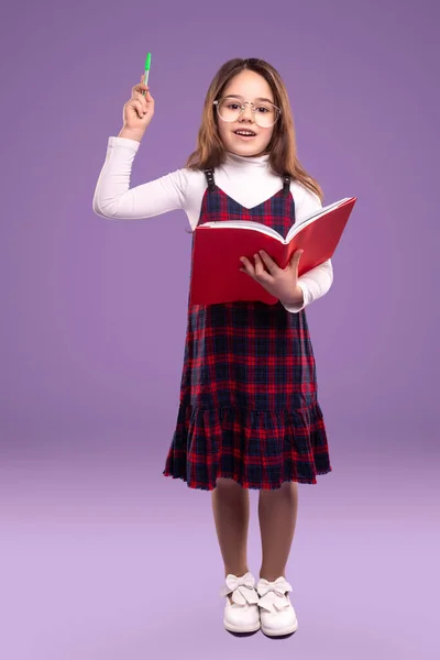 Slimme schoolmeisje met boek en pen — Stockfoto