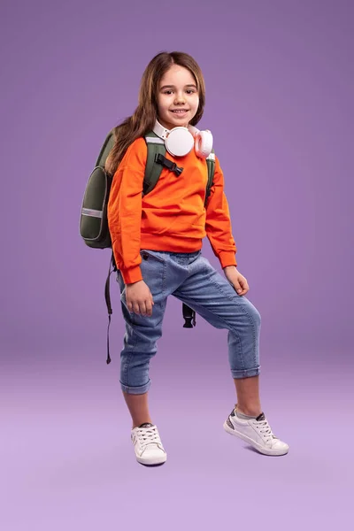 Chica con estilo en traje casual con mochila y auriculares — Foto de Stock