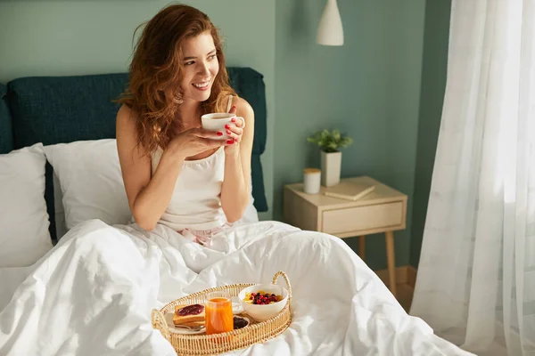 침대에서 아침을 먹고 있는 어린 암컷 — 스톡 사진