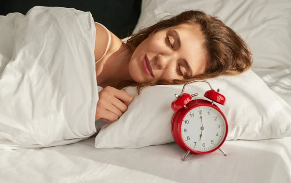 Молода жінка спить біля будильника — стокове фото