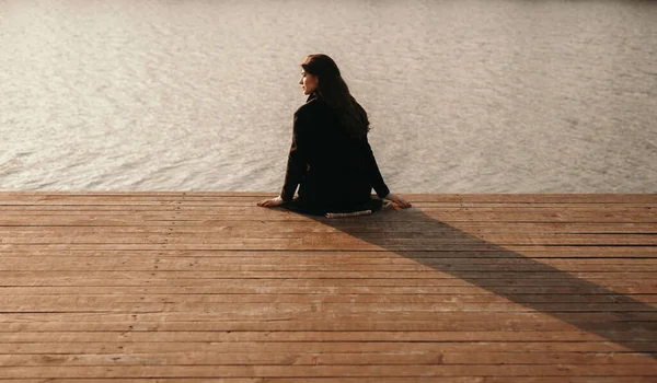 Yalnız kadın nehir kenarındaki iskelede oturuyor. — Stok fotoğraf