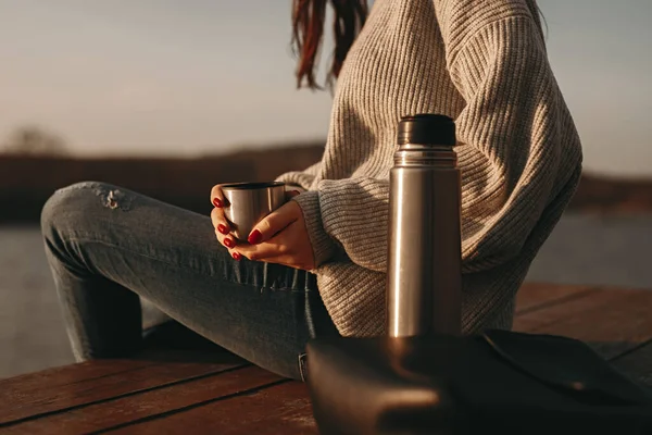 Kvinna med varmt kaffe vilar nära sjön — Stockfoto