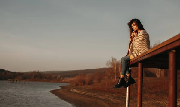 Tenera donna seduta sul molo vicino al laghetto al tramonto — Foto Stock