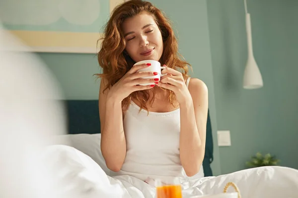 Mujer joven disfrutando del desayuno en la cama —  Fotos de Stock