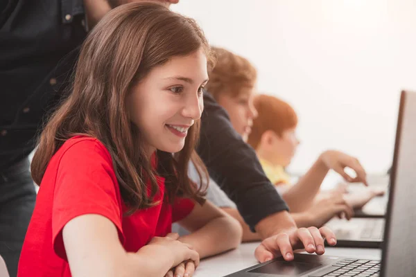 Gelukkig schoolmeisje met leraar met behulp van laptop tijdens les — Stockfoto